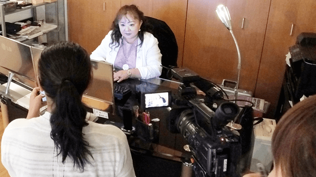 名古屋の探偵 加藤なぎさがテレビ取材を受けている様子（名古屋浮気調査相談室にてテレビカメラを前にインタビューに応じる代表 加藤なぎさ）